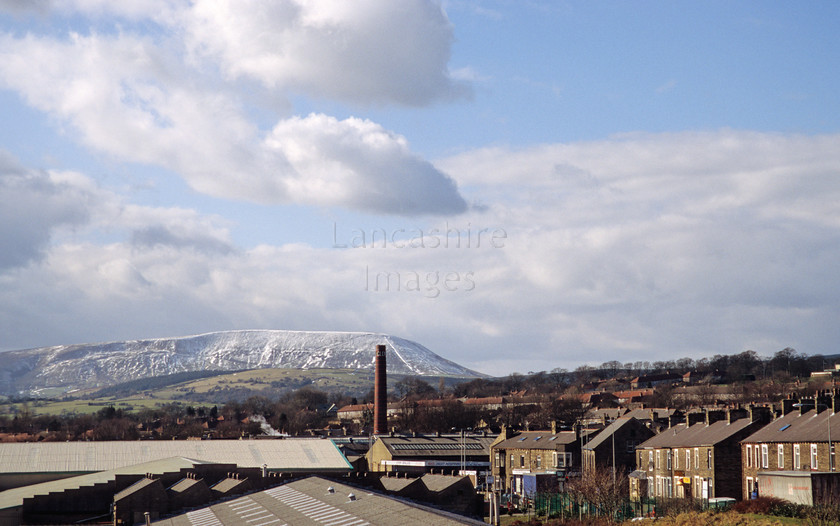 DCP0082 
 Colne in East lancashire with a snow covered Pendle Hill in the background 
 Keywords: Colne Lancashire Lancs England UK Britain industry industrial town street road terrace house factory warehouse storage chimney stack hill snow cloud pollution pollute landscape town and country strength power industrial heartland north northern mill town horizontal DCP0082