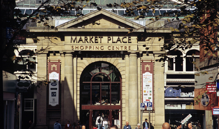 DCP0486 
 Entrance to Market Place shopping centre and indoor market in Bolton 
 Keywords: Lancashire Lancs North West Northwest England UK Britain Europe Bolton town entrance Market Place Shopping Centre indoor market shop commerce business trade tree lined crowd people shoppers pedestrian pedestrianised triange shape architecture building horizontal DCP0486