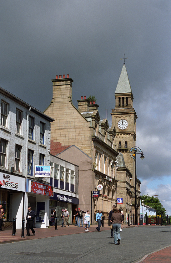 DCP0342 
 Market Street in Chorley town center 
 Keywords: Lancashire Lancs England UK Britain North West Northwest Chorley Town Market Street Shop Shopping Commerce Business Weather Storm Dark Cloud Midday Clock Time Tower Pedestrian Way Architecture Building Vertical DCP0342