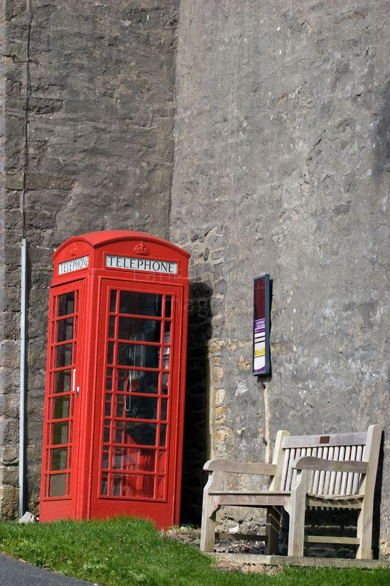 DCP1250 
 Traditional red telephone box in the village of Downham 
 Keywords: Red, Phone, telephone, box, bench, Downham, Lancashire, Lancs, North, West, Northwest, England, UK, Britain, Pendle, village, seat, bus, timetable, stone, wall, traditional, tradition, contrast, contrasting, colour, color, colourful, colorful, Europe, vertical, DCP1250