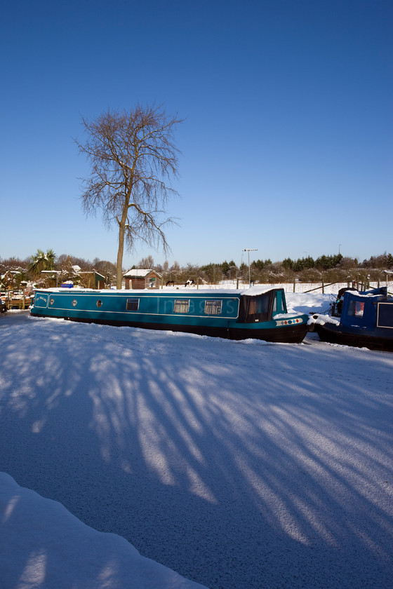 DCP1713 
 Narrow boat on frozen Leeds and Liverpool canal at Adlington 
 Keywords: Adlington, Leeds and Liverpool, Canal, waterway, season, winter, snow, cold, ice, freeze, frozen, tow, path, towpath, narrow, boat, boats, barge, barges, transport, transportation, tree, moored, shadow, shadows, blue, sky, Lancashire, Lancs, Northwest, North, West, England, UK, Britain, Europe, DCP1713